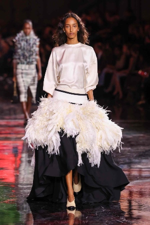 Lady walking down runway in a wedding dress for a fashion show.
